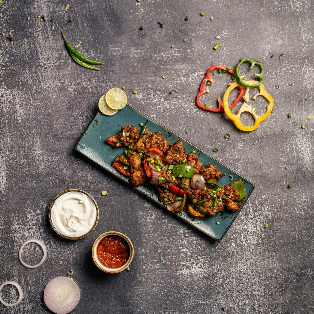 Top-down view of a grilled chicken platter with colorful peppers and sauces, ideal for food photography.