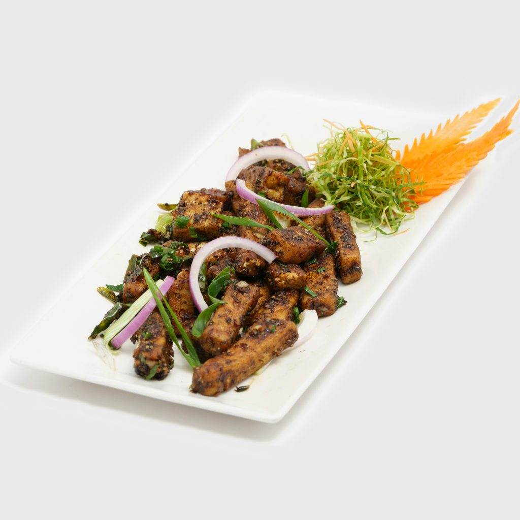 A gourmet plate of stir-fried tofu with crisp vegetables garnished beautifully.